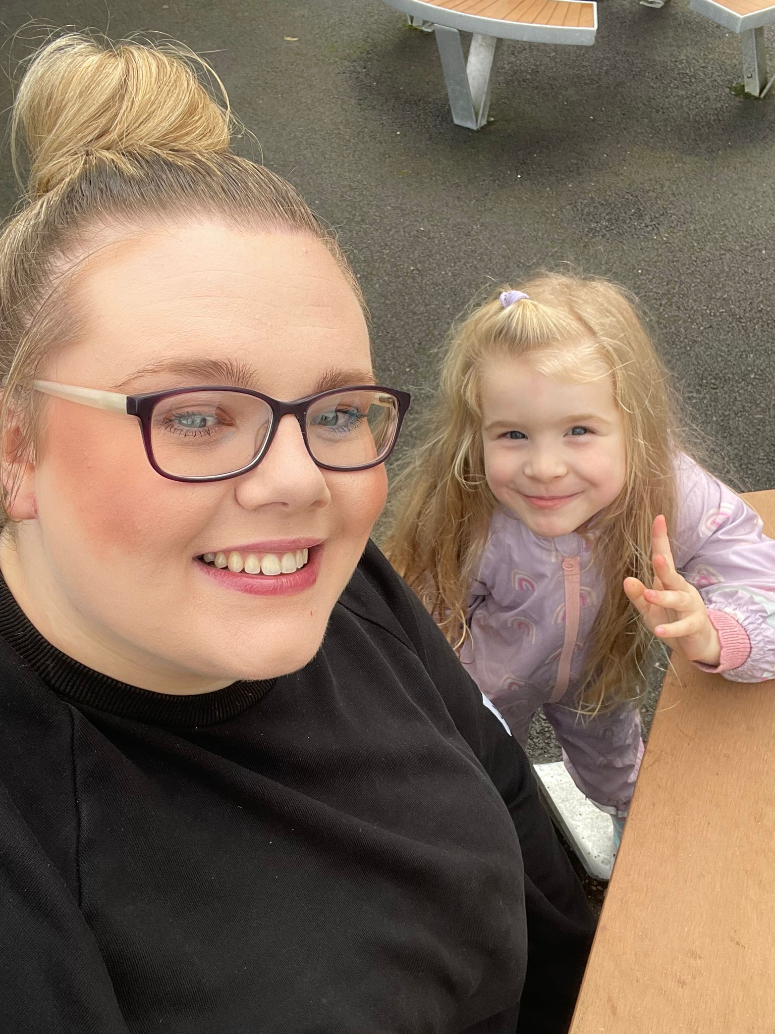 Laura smiling outdoors with a child in her care